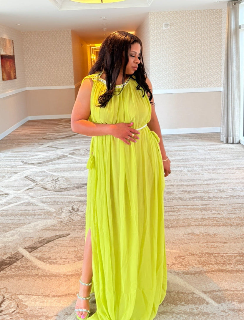 Woman in a bright yellow dress standing in a room with large windows.